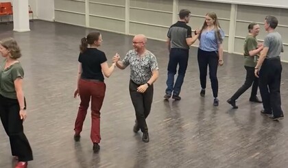 Sex personer dansar pardans i en ljus sal med trägolv.