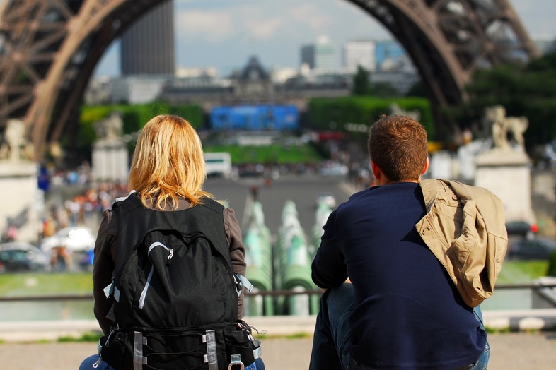 Två personer sitter med ryggen mot kameran och tittar mot Eiffeltornet i Paris.