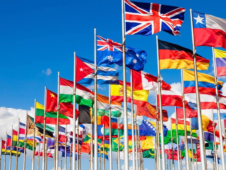 Massor av flaggstänger med olika flaggor som fladdrar i vinden.