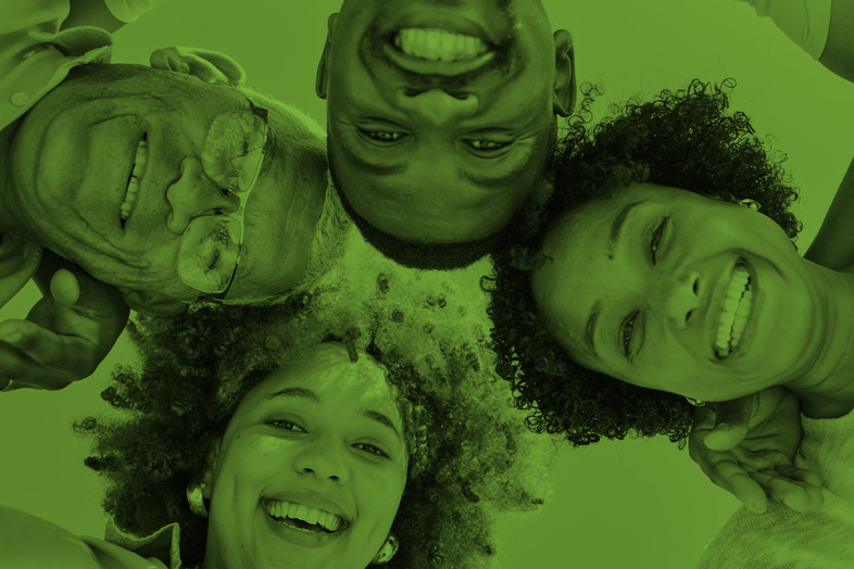 Fyra personer ligger i en cirkel och ler mot kameran, bilden har ett grönt filter.