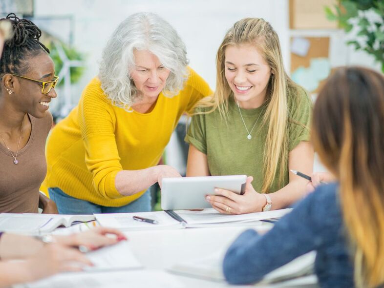 Fem personer arbetar runt ett bord och tittar på en datorpadda.