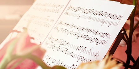 Notblad med noter står på ett notställ, omgivna av färgglada blommor i förgrunden.