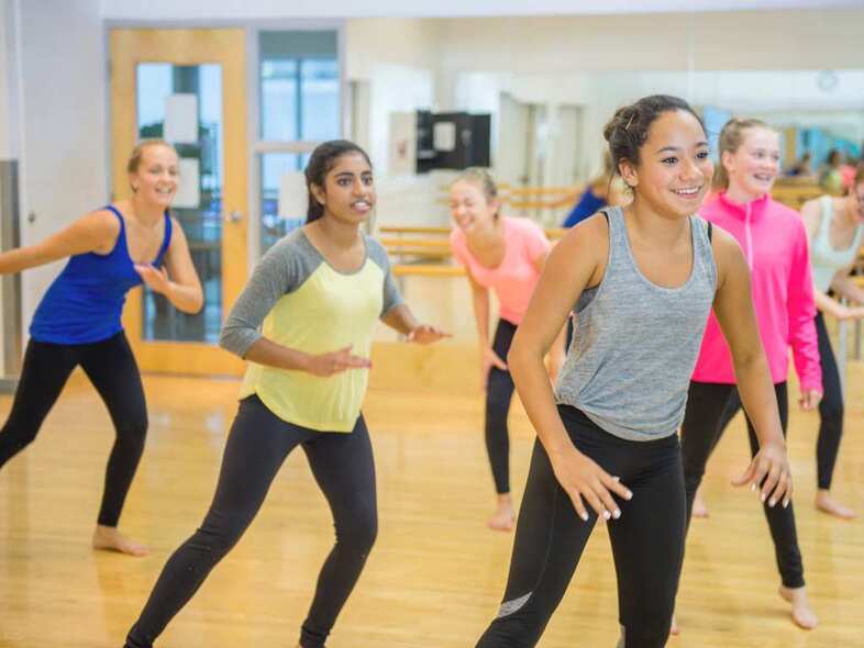 En grupp tonåringar dansar i en gympasal tillsammans.