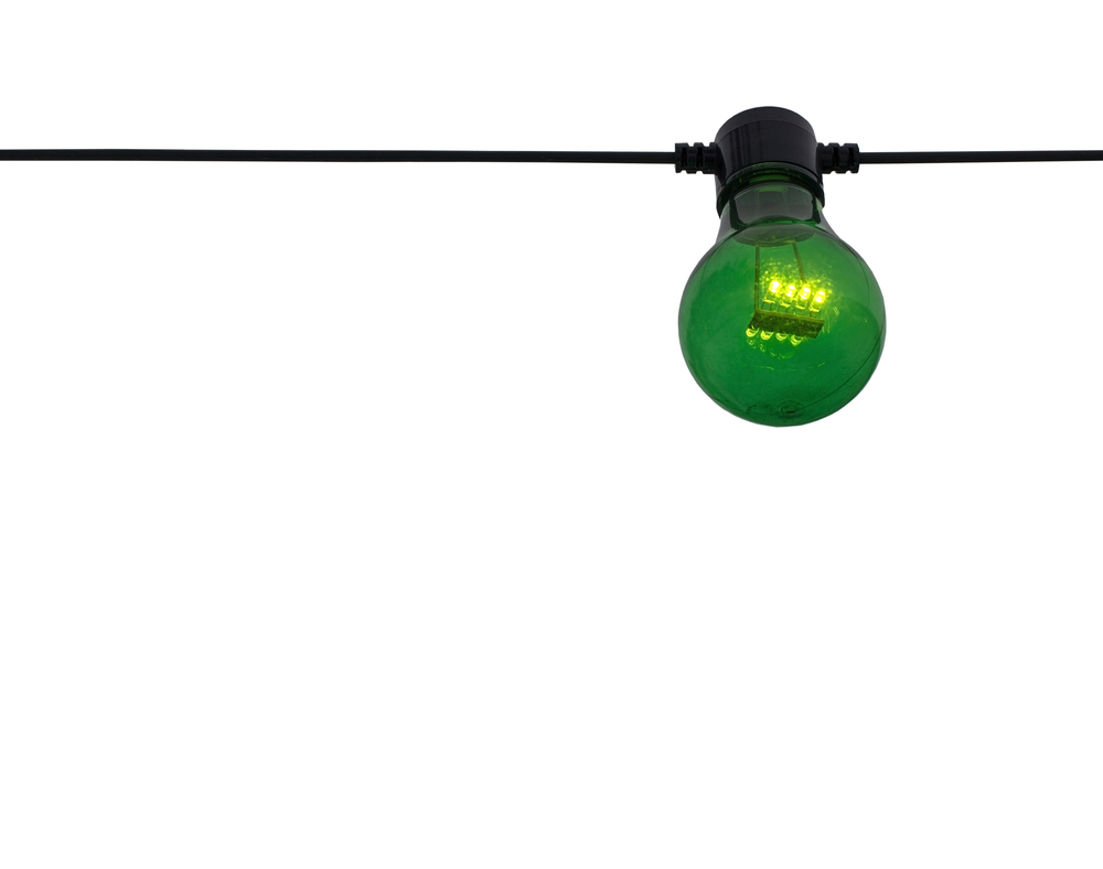 En grön glödlampa hänger i en svart sladd mot en vit bakgrund.