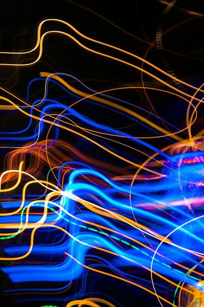 Abstrakt bild med slingrande blå och orange ljuslinjer mot svart bakgrund.
