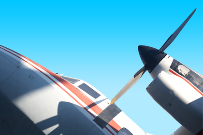 Närbild av ett propellerflygplans motor och vinge mot en klarblå himmel.