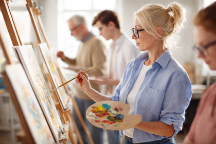 Flera personer målar på stafflier i ett ljust konstnärsateljé.