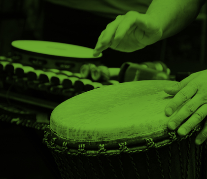 Två händer spelar på en trumma, med fler slagverksinstrument i bakgrunden. Bilden har grön ton.