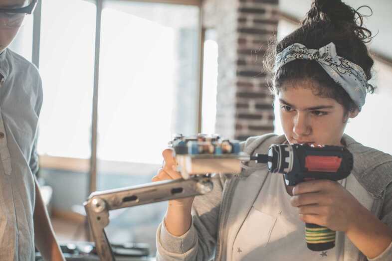 En person borrar koncentrerat i ett föremål som står på en metallarm.