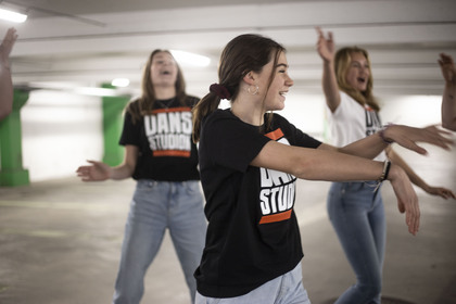 Fyra dansare i parkeringsgarage i Dansstudion-tröjor