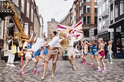 En grupp människor dansar i färgglada kläder på en stadsgata under en festival eller parad.