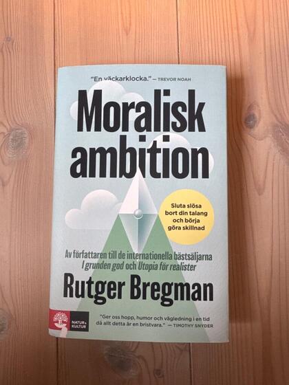 Bokomslag till 'Moralisk ambition' av Rutger Bregman på ett trägolv.