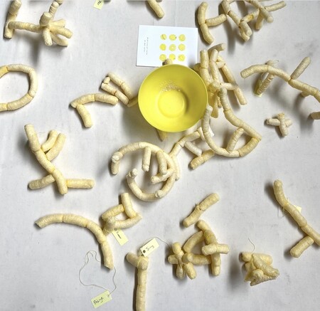 Gula och beige snacks i olika former ligger utspridda på ett bord med en gul skål i mitten.