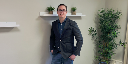 En person står vid väggen i ett mötesrum med bord, stolar, växter och hyllor med krukväxter.