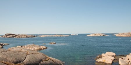 Kustlandskap med släta klippor och blått hav under klar himmel.