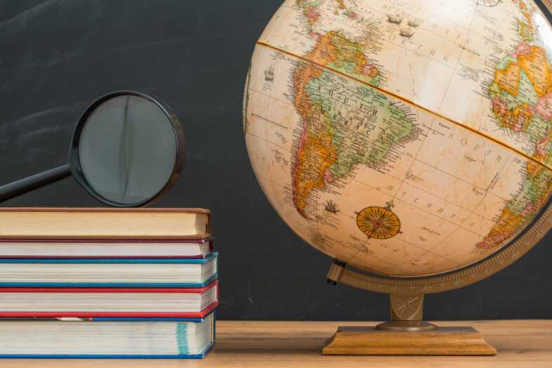 En trave böcker står bredvid en jordglob.