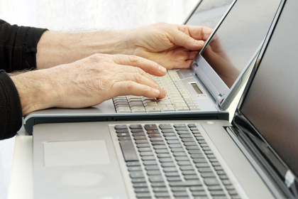 Två bärbara datorer används samtidigt av en person som skriver på tangentbordet.