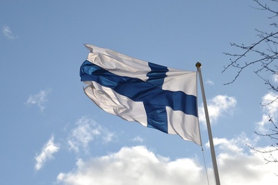 Finlands flagga vajar mot en blå himmel med några moln.