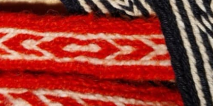 Flera färgglada band i rött, svart och vitt samt lila ligger korslagda på en träyta.