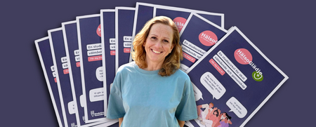 En person i blå tröja står framför flera informationsblad om en studiecirkel för ökat välmående.