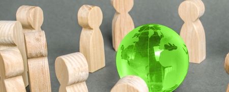 Träfigurer står i en cirkel runt en grön genomskinlig jordglob på grå bakgrund.