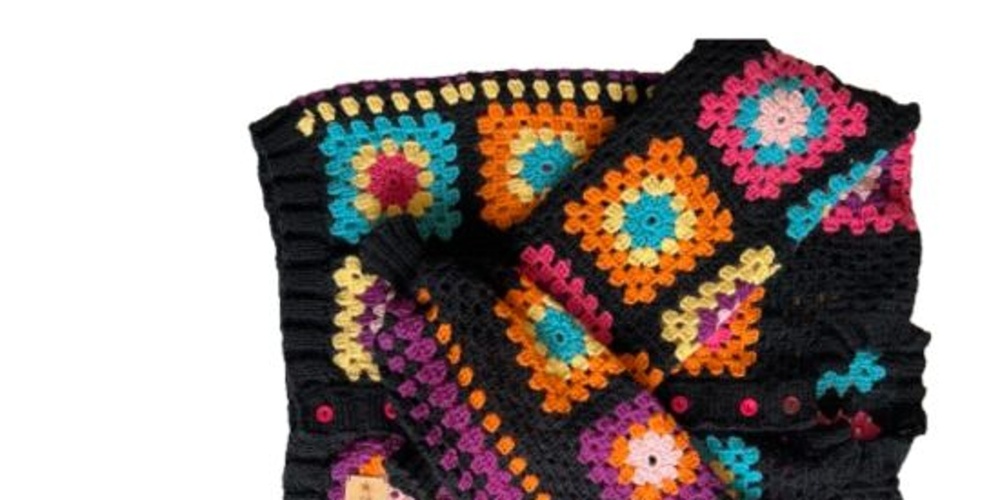 Färgglad virkad filt med mormorsrutor i olika färger på svart bakgrund.