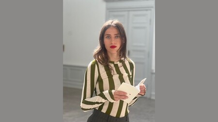 Person i randig grön och vit tröja håller ett öppet kort i ett ljust rum med grå paneldörrar.