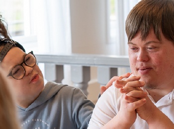 Fyra personer sitter runt ett bord och samtalar. Text om tillgänglighet för alla syns i bilden.