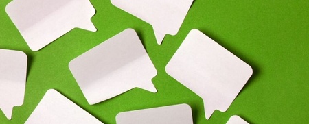 Flera tomma pratbubblor av papper ligger utspridda på en grön bakgrund.