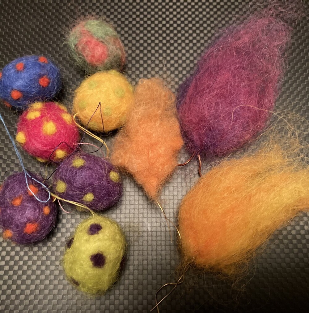 Färgglada ullbollar och former i olika mönster och färger på en mörk bakgrund.