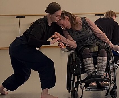 En person i rullstol deltar i en dansövning med en annan person i en dansstudio.
