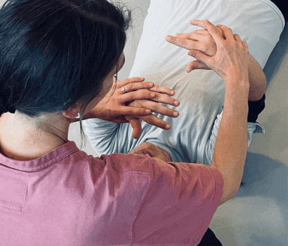 Två personer utför en handövning, en sitter och en ligger ner, händerna är i fokus.