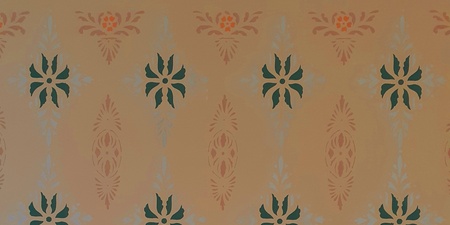 Vägg med symmetriskt mönster i grönt, orange och beige mot en ljus bakgrund.