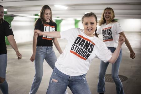 Fyra dansare i parkeringsgarage i Dansstudion-tröjor