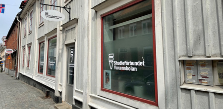 Fasad av en byggnad med skyltar för Studieförbundet Vuxenskolan på ett fönster och en dörr.