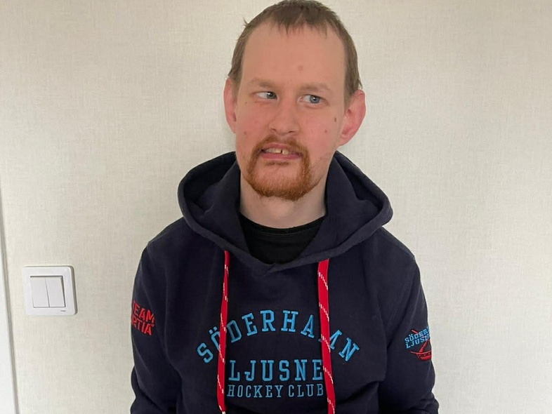 Person i mörkblå hoodie med texten 'Söderhamn Ljusne Hockey Club' står inomhus mot ljus vägg.