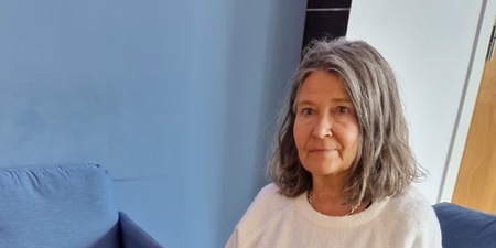 Kvinna sitter i ett vardagsrum bredvid ett soffbord med dekorationer av tyg och stenar.