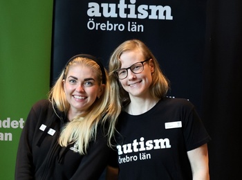 Två personer står vid ett informationsbord med broschyrer om autism och vuxenutbildning.