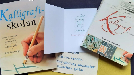 Två böcker om kalligrafi, ett öppet kort och papper med handskriven text på svenska.