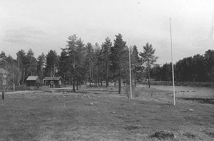 En svartvit bild med en gård för förr med träd omkring.