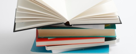 En hög med böcker där den översta boken är uppslagen och resten är stängda, mot vit bakgrund.