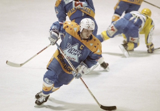 Ishockeyspelare i blått och gult lag dribblar med pucken på isen under en match.