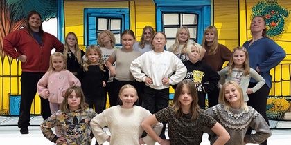 En grupp människor i olika åldrar står framför ett hus i glada färger.