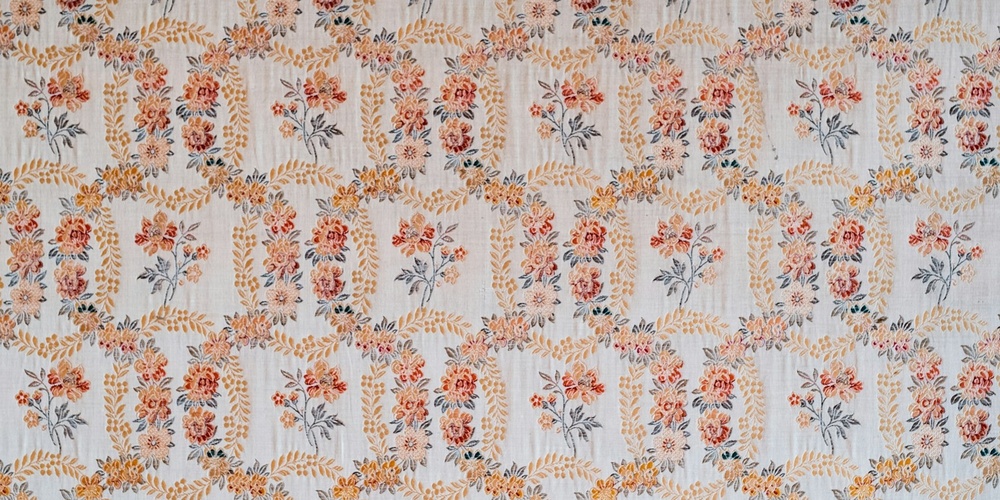 Blommigt mönster på tapet i ljusa färger med inslag av orange, gult och blått.