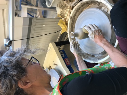 En person drejar en vas på en elektrisk drejskiva i en keramikverkstad.