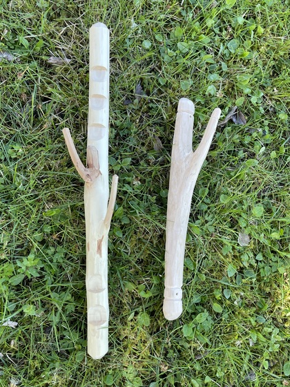 Två Y-formade träpinnar ligger på gräs, täljde och bearbetade för hand.