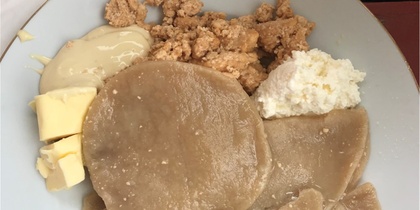 En tallrik med nigeriansk yam fufu, serverad med smör, jordnötssmulor och vit sås.