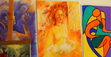 Tre färgstarka målningar på en vägg, varav en föreställer en kvinna med ett barn.