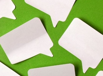 Flera tomma pratbubblor av papper ligger utspridda på en grön bakgrund.