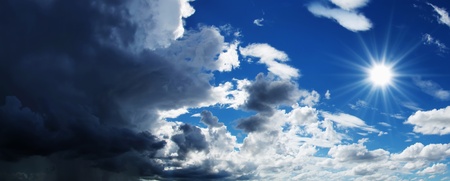 Dramatisk himmel med mörka moln till vänster och klarblå himmel med sol till höger.